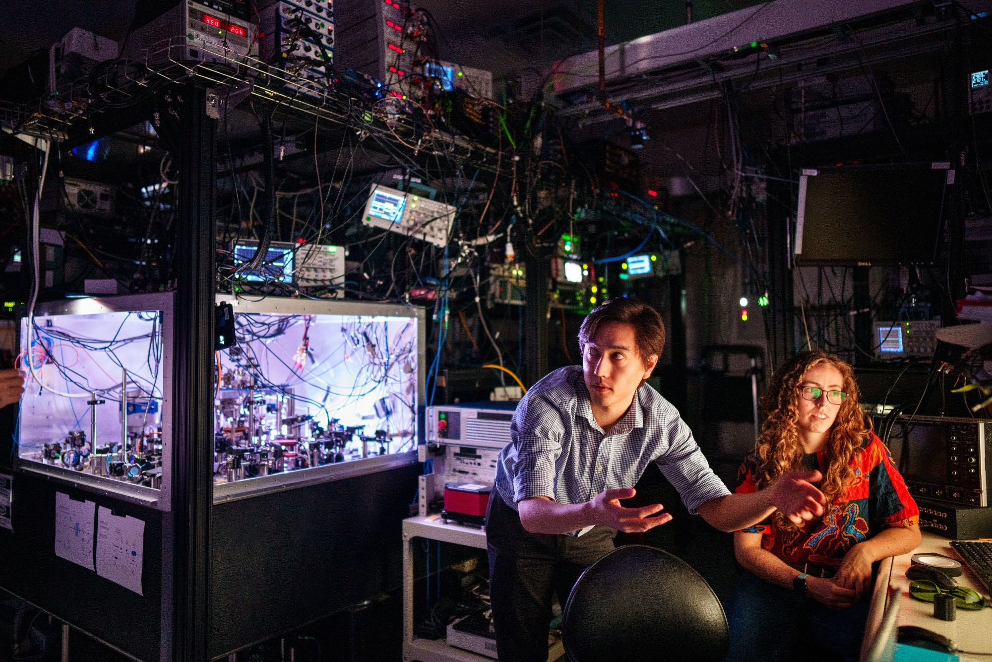 Matthew Chow, center, and Bethany Little discuss with Yuan-Yu Jau, off camera, the first practical way to detect atom loss for neutral atom quantum computing at Sandia National Laboratories.